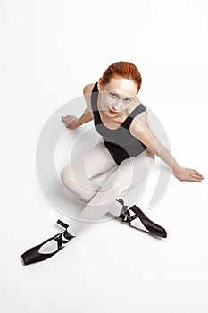 Sport Ideas. Portrait of Positive Caucasian Professional Ballet Dancer in Body Suit  and Pointes Shoes Posing Against White