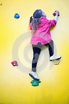Sport image of climbing little girl to top of wall