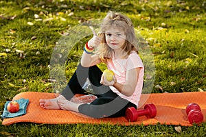 Sport kids boy. Healthy lifestyle and healthy food concept. Little boy child in sportswear eating apple sitting on sport