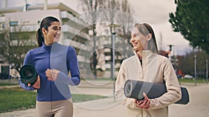 Sport ladies talking on walk at spring neighbourhood. Close up friends laughing