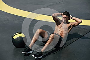 Sport man doing abs crunches exercise, fitness workout at street