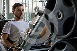 sport man doing exercises with leg press machine in fitness gym . workout . training