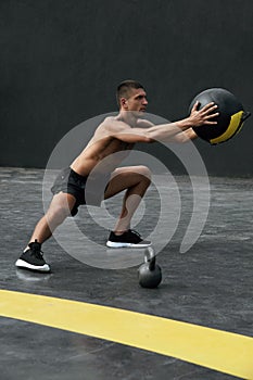 Sport man doing side lunge exercise with med ball at fitness gym