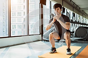 Sport man doing squat posture on yoga mat in fitness gym at condominium in urban. People lifestyles and Sport workout concept photo