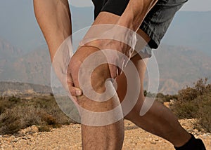 Sport man holding his knee in pain injured when running outdoors