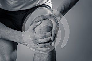 Sport man injured when exercising or running holding his knee in pain