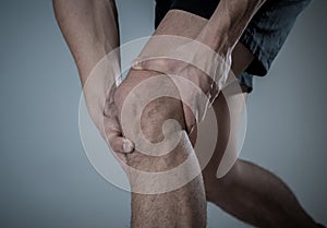 Sport man injured when exercising or running holding his knee in pain