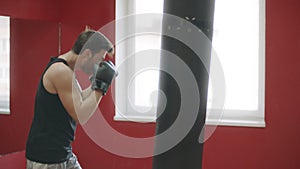 Sport man punching boxing bag at training. Kickboxer training in fight club