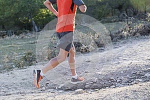 sport man with ripped athletic and muscular legs running downhill off road in jogging training workout