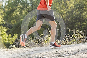 sport man with ripped athletic and muscular legs running downhill off road in jogging training workout