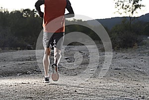 Sport man with ripped athletic and muscular legs running uphill off road in jogging training workout