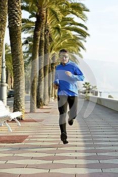 Sport man running along beach palm trees boulevard in morning jog training session