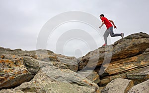 Sport man running, jumping over rocks in mountain area.