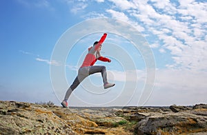 Sport man running, jumping over rocks in mountain area.