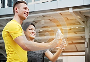 Sport Man and Sport Girl drinking water on street.