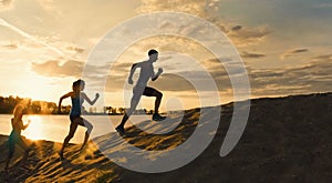 Sport motivations -group of athletes - two girls and a guy are fleeing the mountain, near river at dusk