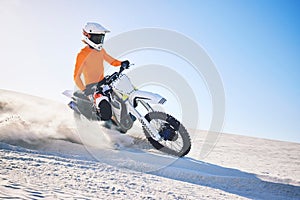 Sport, motorbike and athlete with desert with sand on wheels, pride and skill for adrenaline. Biker, sunshine and dust