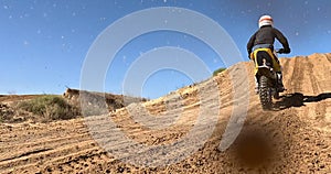 Sport, motorbike and person driving in desert, sand or jump on hill for off road stunt on path. Dirt, trail and driver