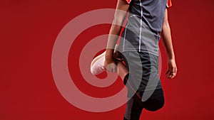Sport is my passion. Cropped shot of a teenage boy in sportswear stretching his legs. Isolated on red background. Sport