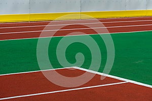 Sport, part of the playing field covered with red and green artificial turf with white markings and a white wall separated by a