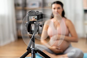 pregnant woman or yoga blogger with camera at home