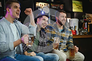 Sport, people, leisure, friendship, entertainment concept - happy male football fans or good yuong friends drinking beer