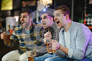 Sport, people, leisure, friendship, entertainment concept - happy male football fans or good yuong friends drinking beer