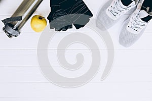 Sport photo. Healthy lifestyle. Bottle for water, apple and leather gloves. Stylish trainers. White wooden background. Perfect