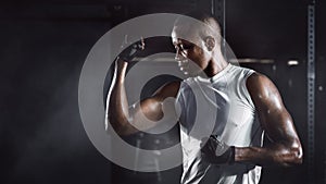 Sport portrait of african american athletics strong bodybuilder man posing show his muscle in gym in dark tone