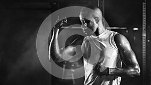 Sport portrait of african american athletics strong bodybuilder man posing show his muscle in gym in dark tone in black and white