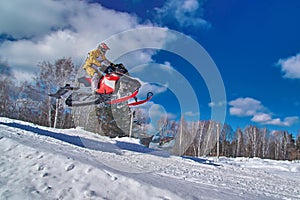 Sport red snowmobile jump. Clear sunny winter day. Concept quick movement. photo