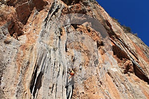 Sport rock climber on challenging climbing route