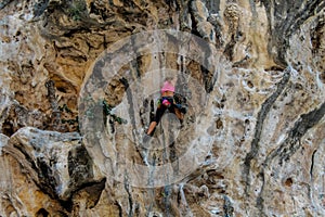 Sport rock climber on challenging climbing route with stalactite in Thailand Ton Sai
