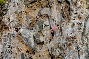Sport rock climber on challenging climbing route with stalactite in Thailand Ton Sai