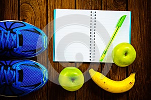 Sport shoes, apples and bananas on a wooden background. Sport