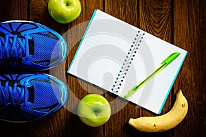 Sport shoes, Apples and bananas on a wooden background. Sport