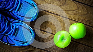 Sport shoes and apples on a wooden background. Sport equipment