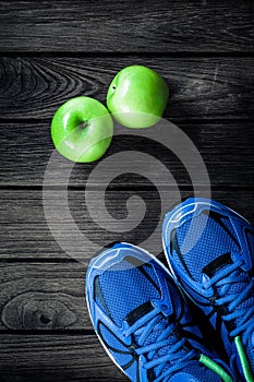 Sport shoes and apples on a wooden background. Sport equipment