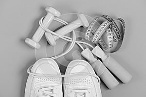 Sport shoes and equipment for healthy shape. Sneakers with skipping rope and tape on green background.