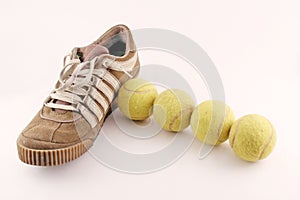 Sport shoes next to 4 tennis balls