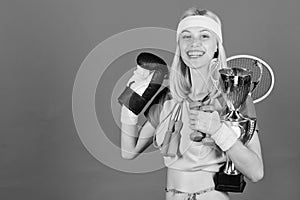 Sport shop assortment. Girl successful modern woman hold golden goblet of sport champion and equipment blue background