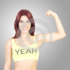 Sport smiling woman shows off his muscles on gray background. Sports and fitness