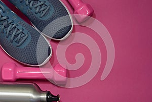 Sport sneakers and dumbbells on pink background with copy space for text. Sport objects background. Sports concept