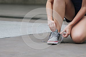 Sport sneakers footwear young woman knelt down do up shoelaces. Ready running shoes in sport exercise jogging person. Close up