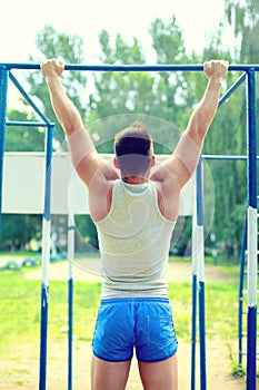 Sport, street workout concept - athlete doing pull ups on the horizontal bar