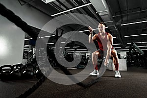 Sport. Strong man exercising with battle ropes at the gym with. Athlete doing battle rope workout at gym. Dramatic