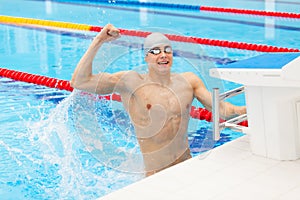 Sport swimmer winning. Man swimming cheering celebrating victory success smiling happy in pool wearing swim goggles and