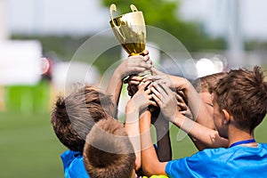 Sport team celebrate success. Happy boys rising golden cup on celebration