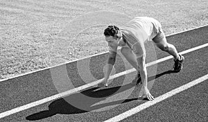 Sport tips from professional runner. Man athlete runner stand low start position stadium path. Make effort for victory