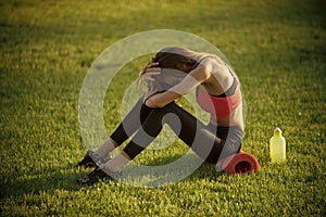 Sport, training, workout. Health, bodycare, wellness. Sportswoman sit on green grass with gym equipment on summer